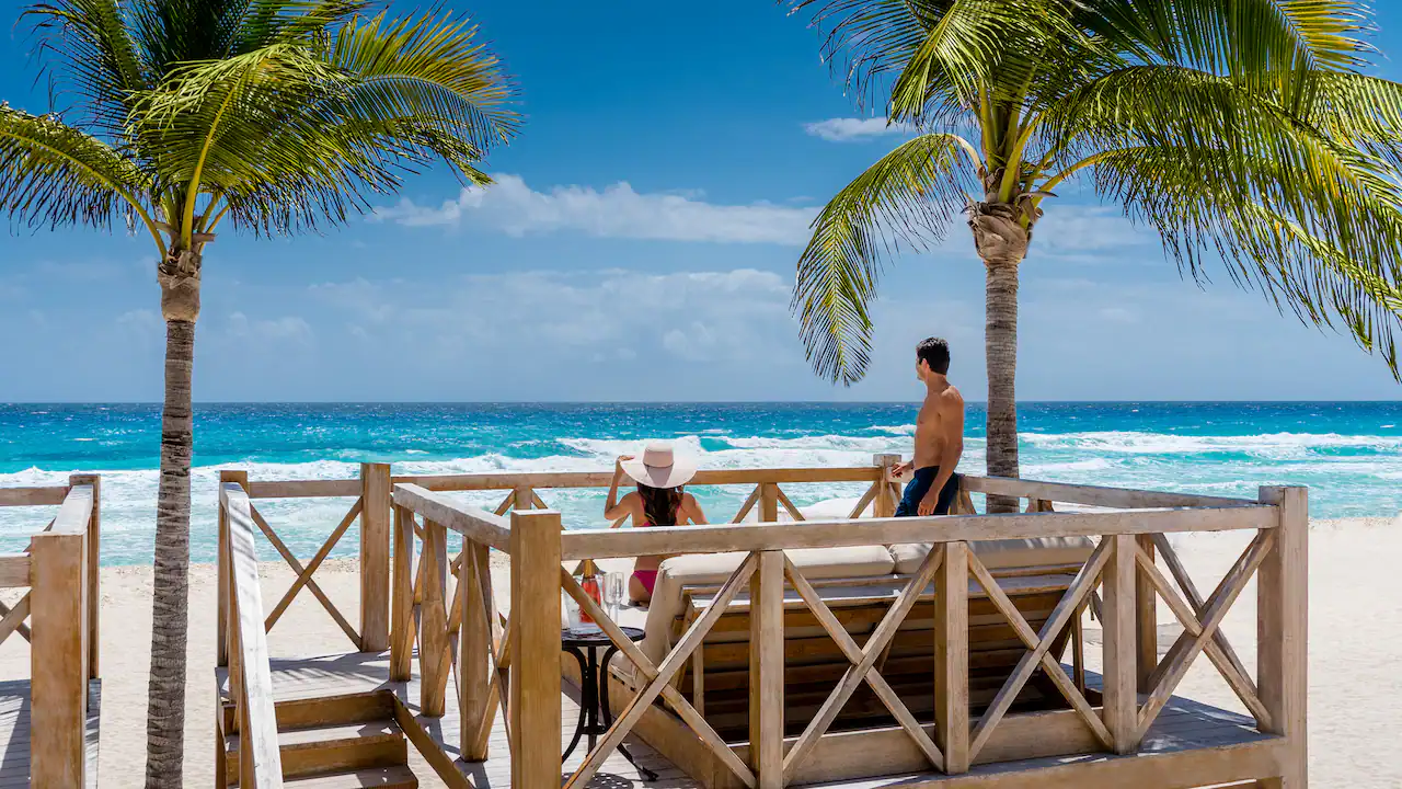 Couple relaxing in a beachfront cabana overlooking the Caribbean Sea at Hyatt Zilara Cancun.